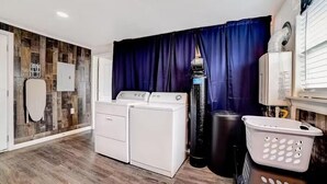 A laundry room with two white washing machines, a large black water heater, and a white laundry basket. - dog-friendly home with fenced yard, grill, sunroom (San Antonio)