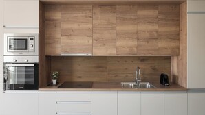 A modern kitchen with wooden cabinetry, a built-in microwave, oven, and a coffee maker. - Athens Luxury Ethereal View (Zografos)