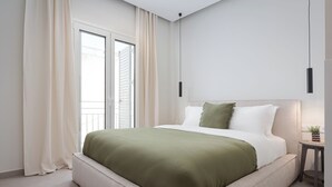 A modern bedroom with a large bed, a small bedside table, and a view of the outdoors through a sliding door. - Athens Luxury Ethereal View (Zografos)