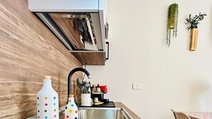 Una cucina moderna con piano cottura a induzione nero, mobili in legno e lavello in acciaio inossidabile.