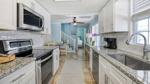 A modern kitchen with white cabinets, a stainless steel range, a microwave, and a granite countertop.