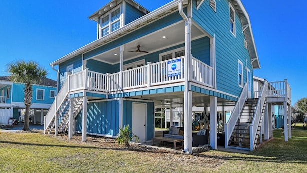 A two-story blue house with a balcony, a porch, and a staircase.