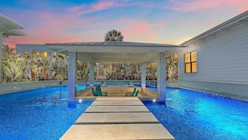 Relax by the serene pool surrounded by lush tropical vegetation and a shaded patio.