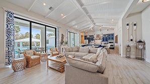 A spacious living room with a large sofa, wicker chairs, and a wooden coffee table.