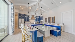 A modern kitchen with a central island, blue cabinetry, and pendant lighting.