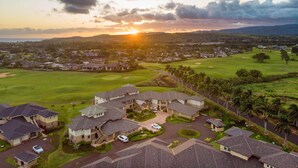 Un quartiere residenziale con case, un campo da golf e un tramonto sullo sfondo.