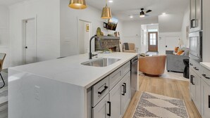 A modern kitchen with a large island, stainless steel appliances, and pendant lighting.