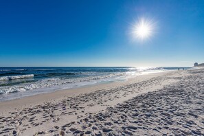A beach with footprints, waves, and a clear sky.