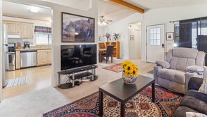 A modern living room with a TV, comfortable seating, and a dining area in the background. - Lincoln Lodge 2 Bedroom Cabin by Yosemite Region Resorts (Groveland)