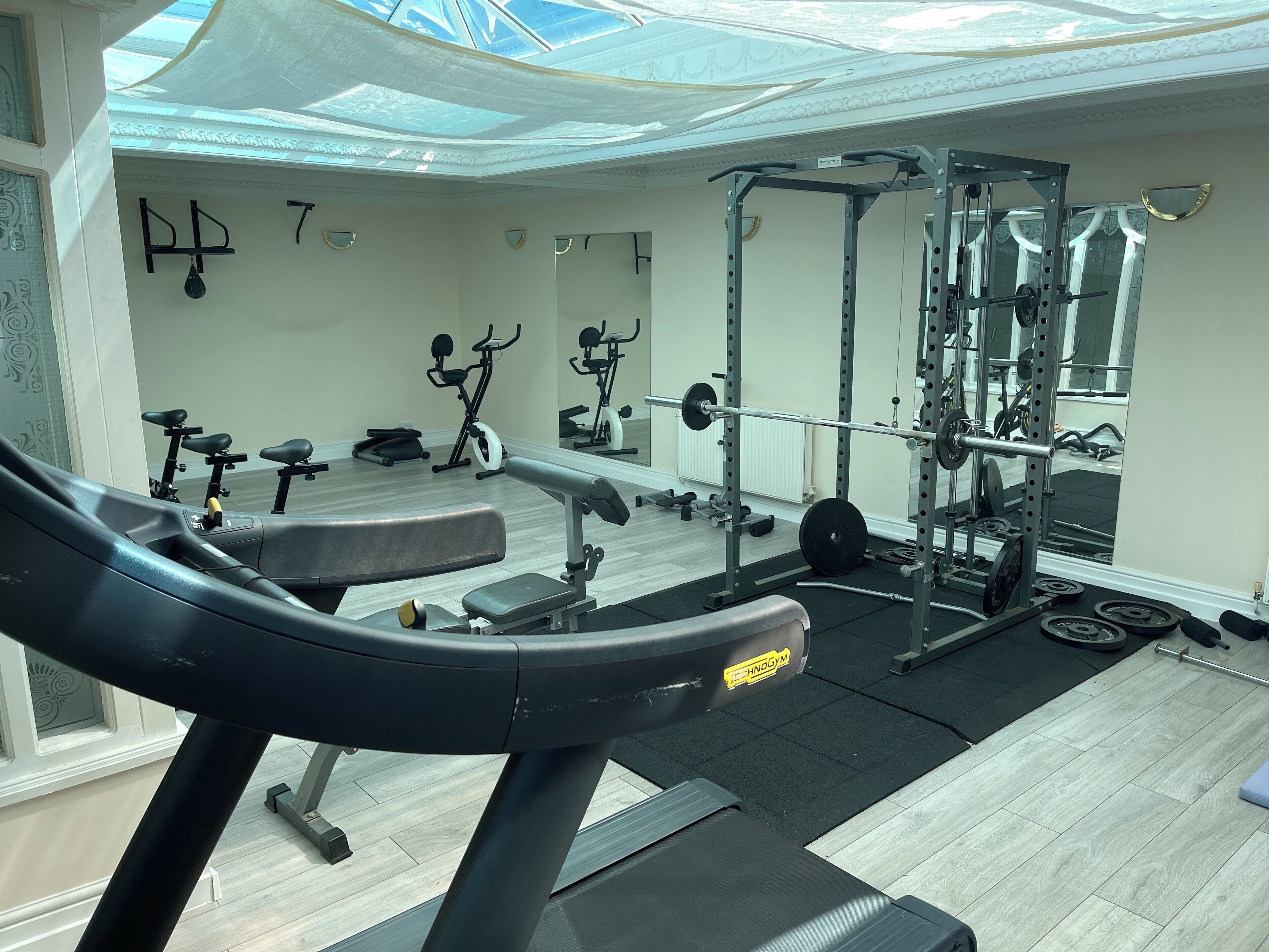 Un gimnasio con equipo de ejercicio, un espejo grande y tragaluces.