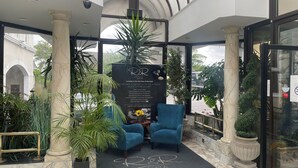A hotel lobby with marble flooring, a reception desk, blue armchairs, and a large potted plant. - Durrant House Hotel  (Bideford)