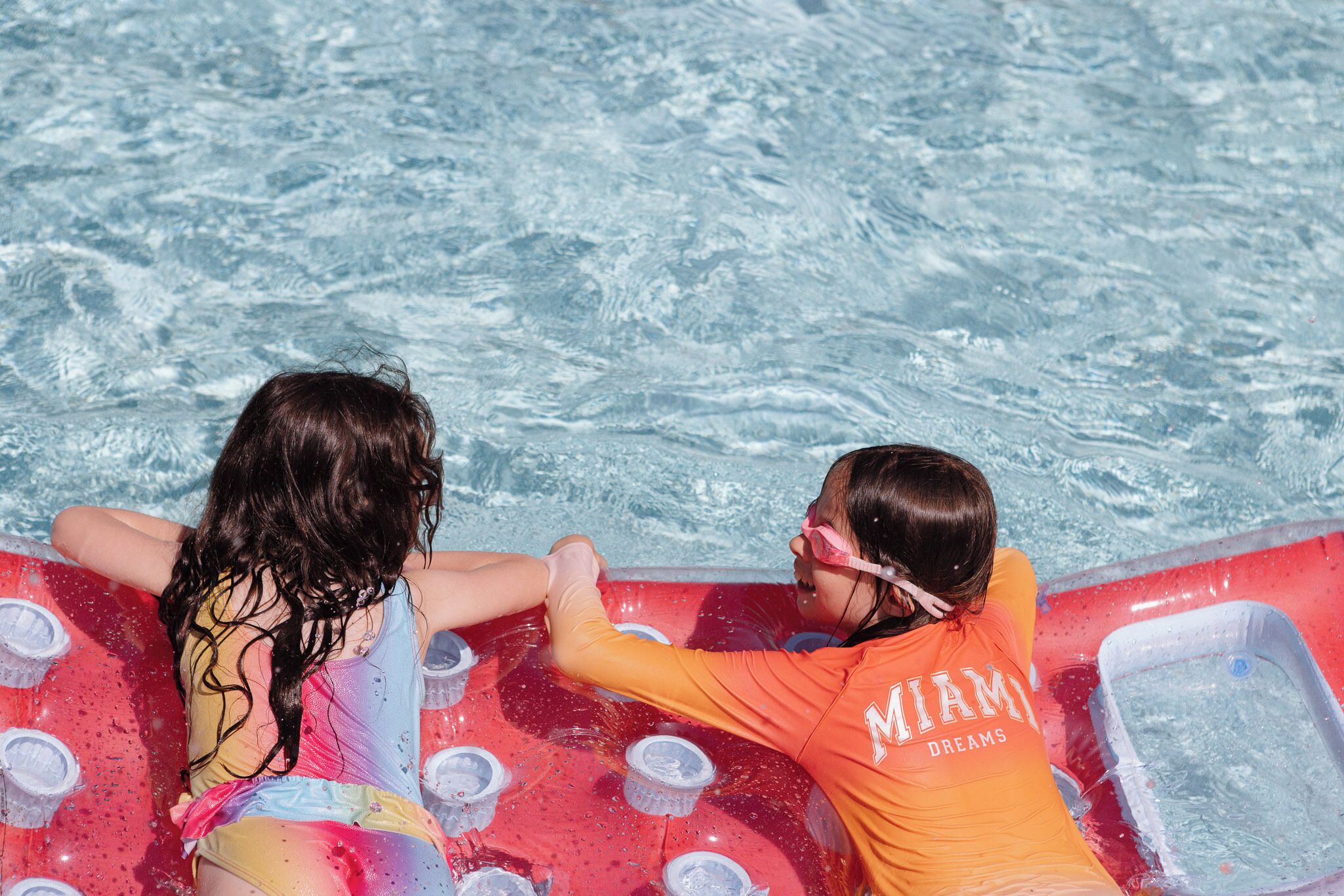Dos personas en una piscina con una balsa inflable.