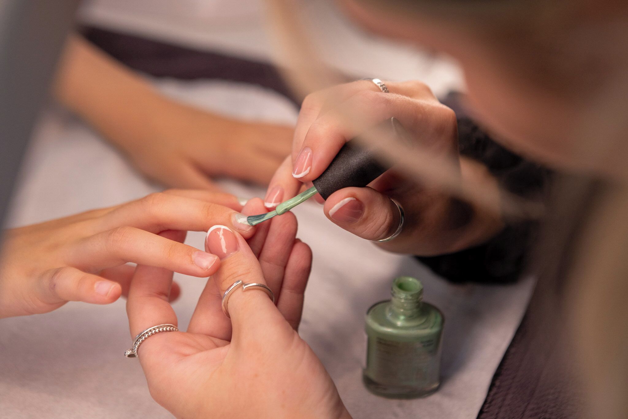 A close-up of a person applying nail polish to another person's nails.