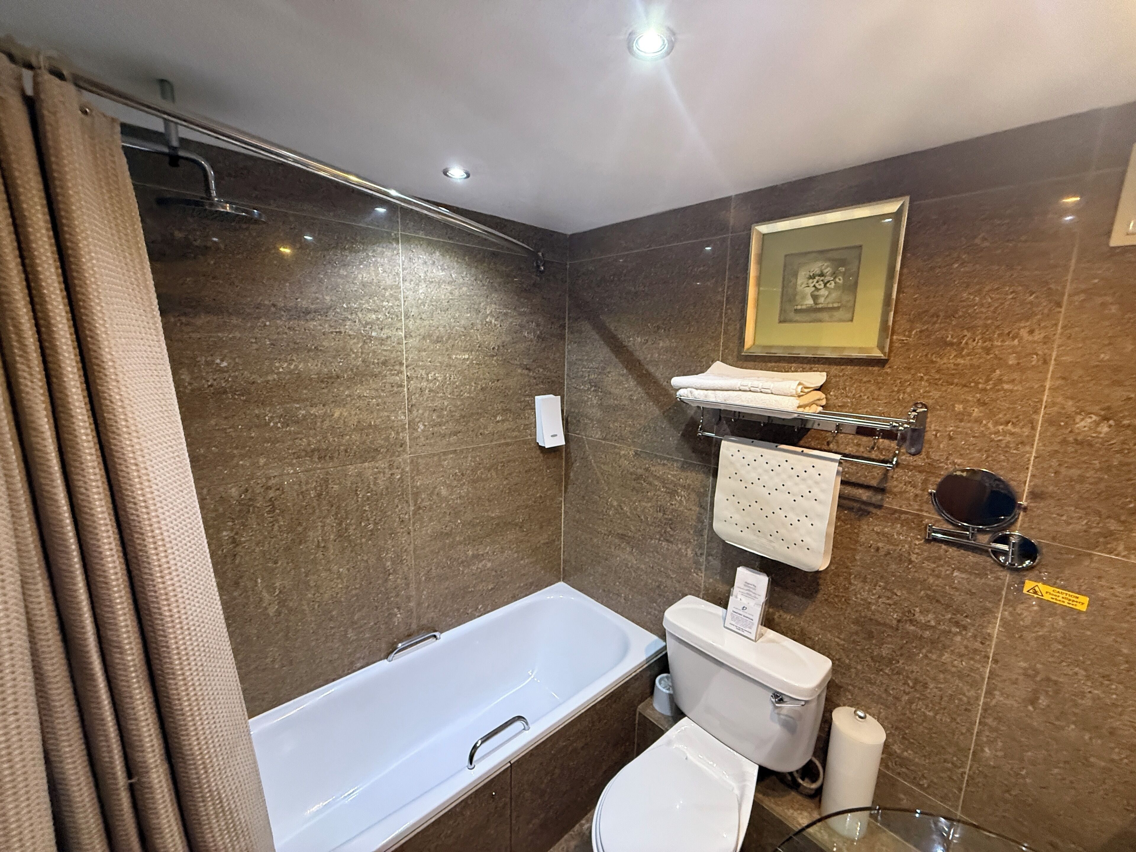 A bathroom with a bathtub, toilet, and a towel rack with towels.