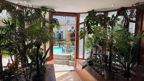 A room with large windows, a wooden bench, and various potted plants. - Durrant House Hotel  (Bideford)