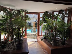 A room with large windows, a wooden bench, and various potted plants. - Durrant House Hotel  (Bideford)