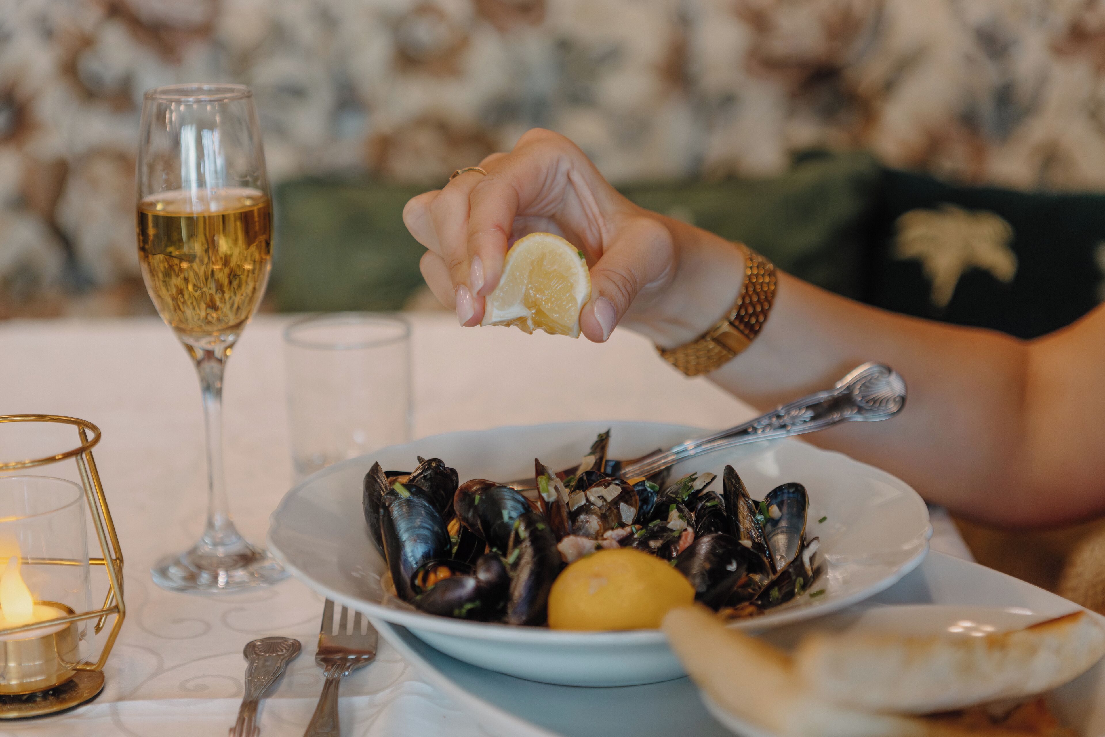 Un tavolo imbandito con un piatto di cozze, un limone e un bicchiere di vino bianco.