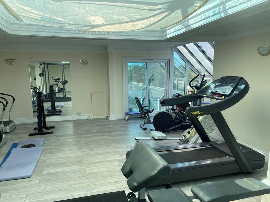 A gym with treadmills, exercise bikes, and a mirrored wall.