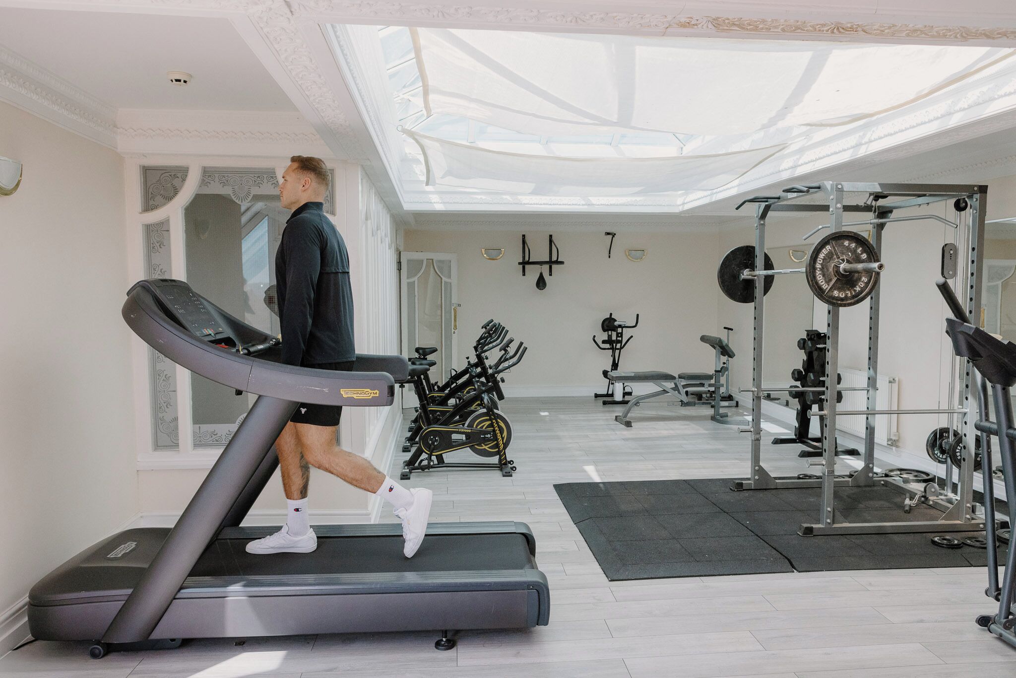 Et fitnesscenter med løbebånd, spinningcykler og styrketreningsudstyr.