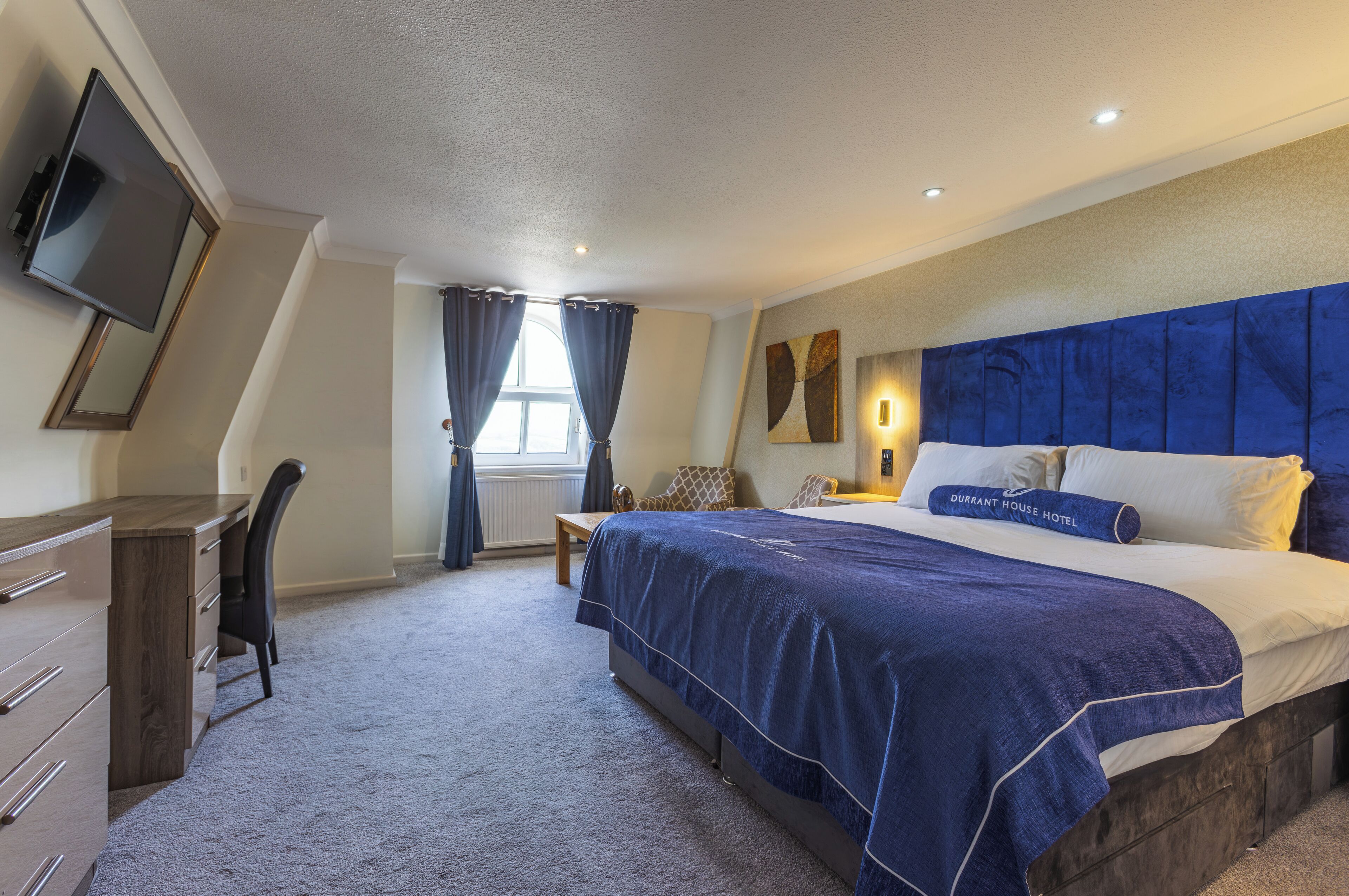 A bedroom with a bed, a desk, and a chair.