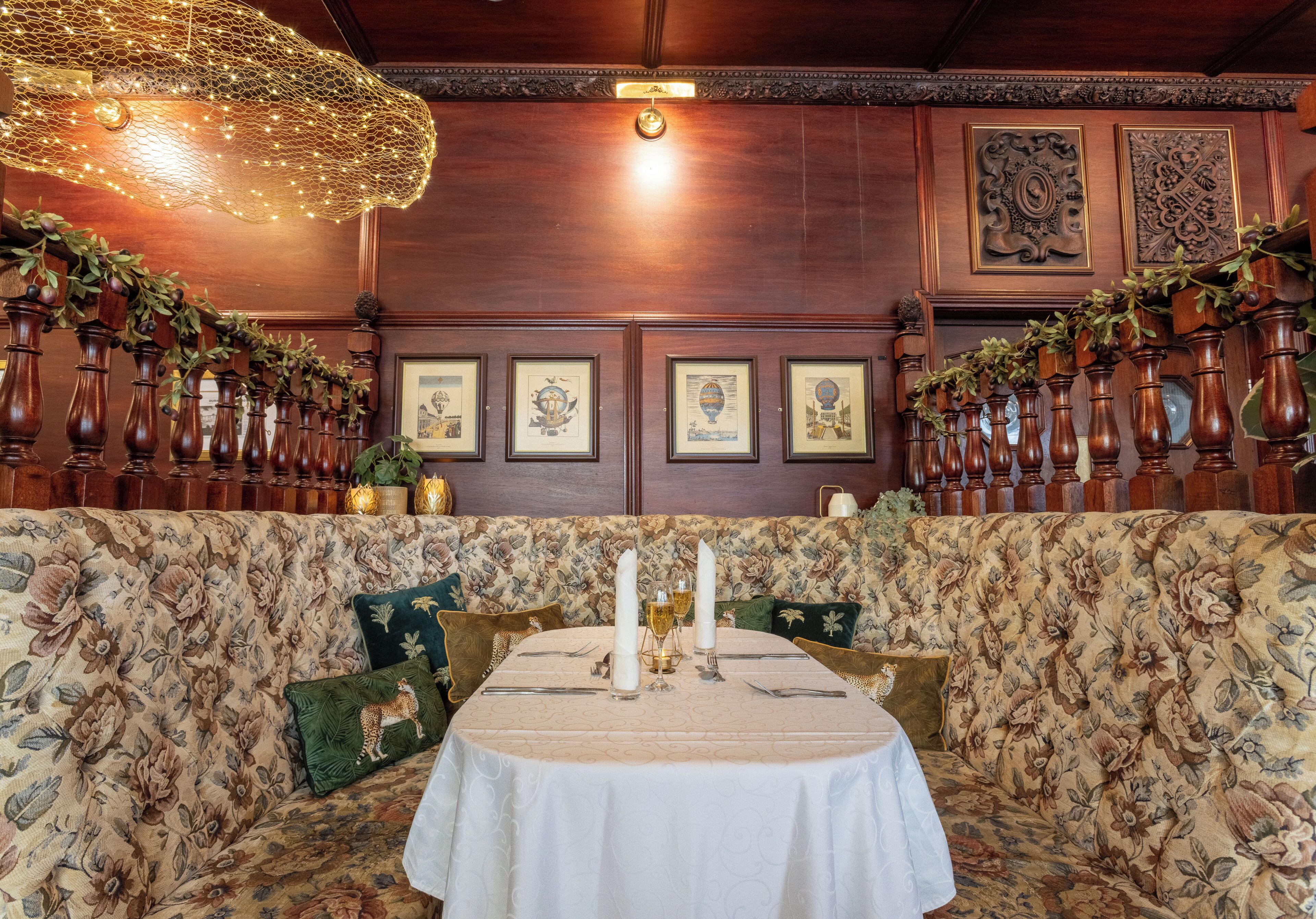 A dining area with a round table set for four, surrounded by a floral-patterned sofa.
