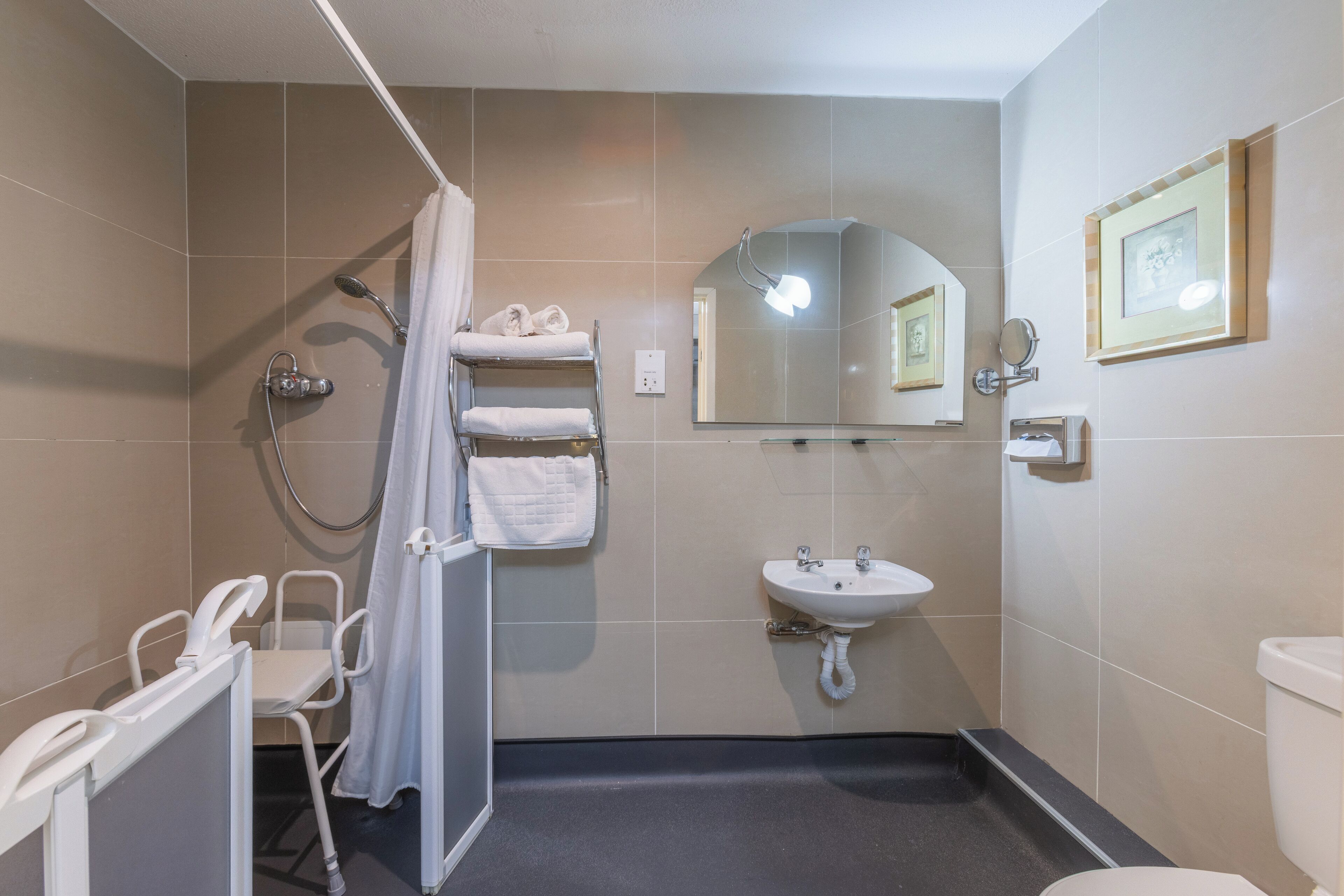 Un bagno con doccia, lavandino, wc e specchio.