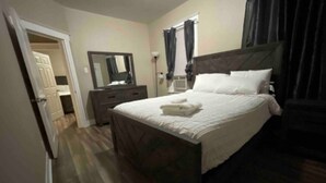 Une chambre à coucher avec un lit, une commode, un miroir et une fenêtre avec des rideaux.