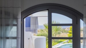 A view through a window with a towel hanging on a rack, a pool, and greenery outside. - Argana Naxos private villa with pool and garden (Plaka)