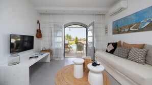 A modern living room with a TV, a guitar, a sofa, and a painting. - Argana Naxos private villa with pool and garden (Plaka)