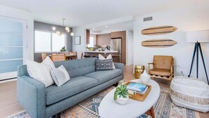 A modern living room with a sofa, coffee table, and decorative items. A kitchen is visible in the background.