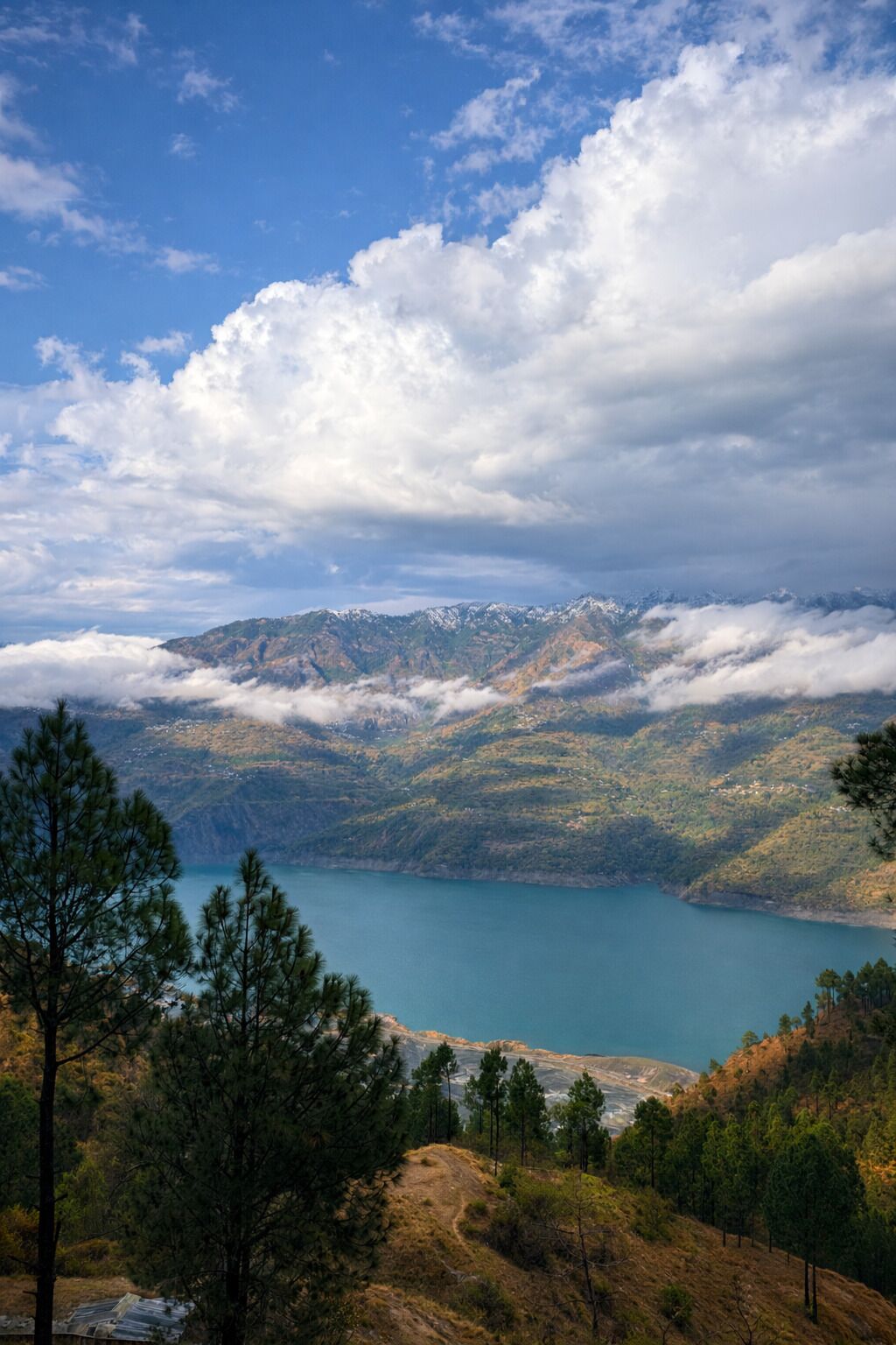 A mountainous landscape with a lake, trees, and a clear sky.