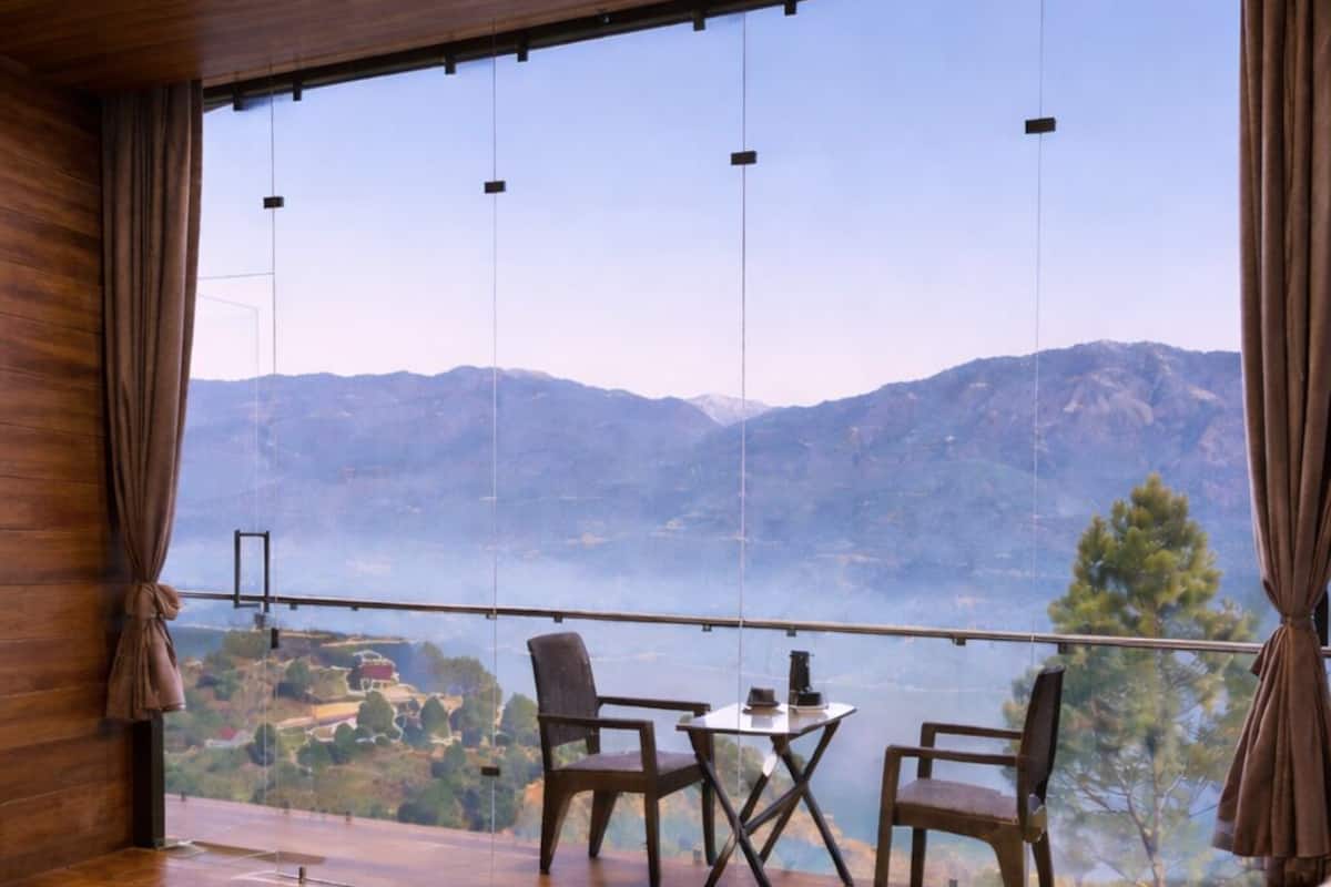 A bedroom with a large window, wooden ceiling, and a view of mountains.