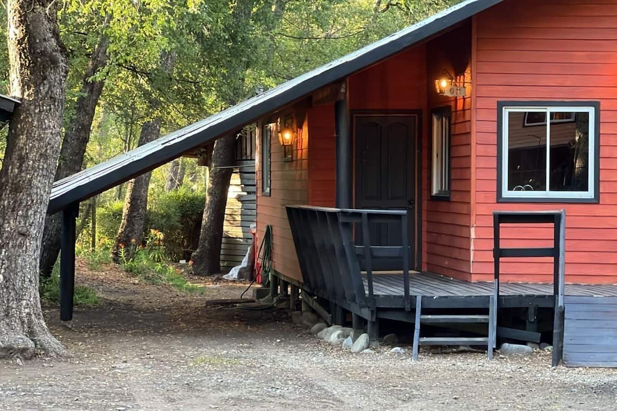A red cabin with a wooden deck and a ramp leading to the entrance.
