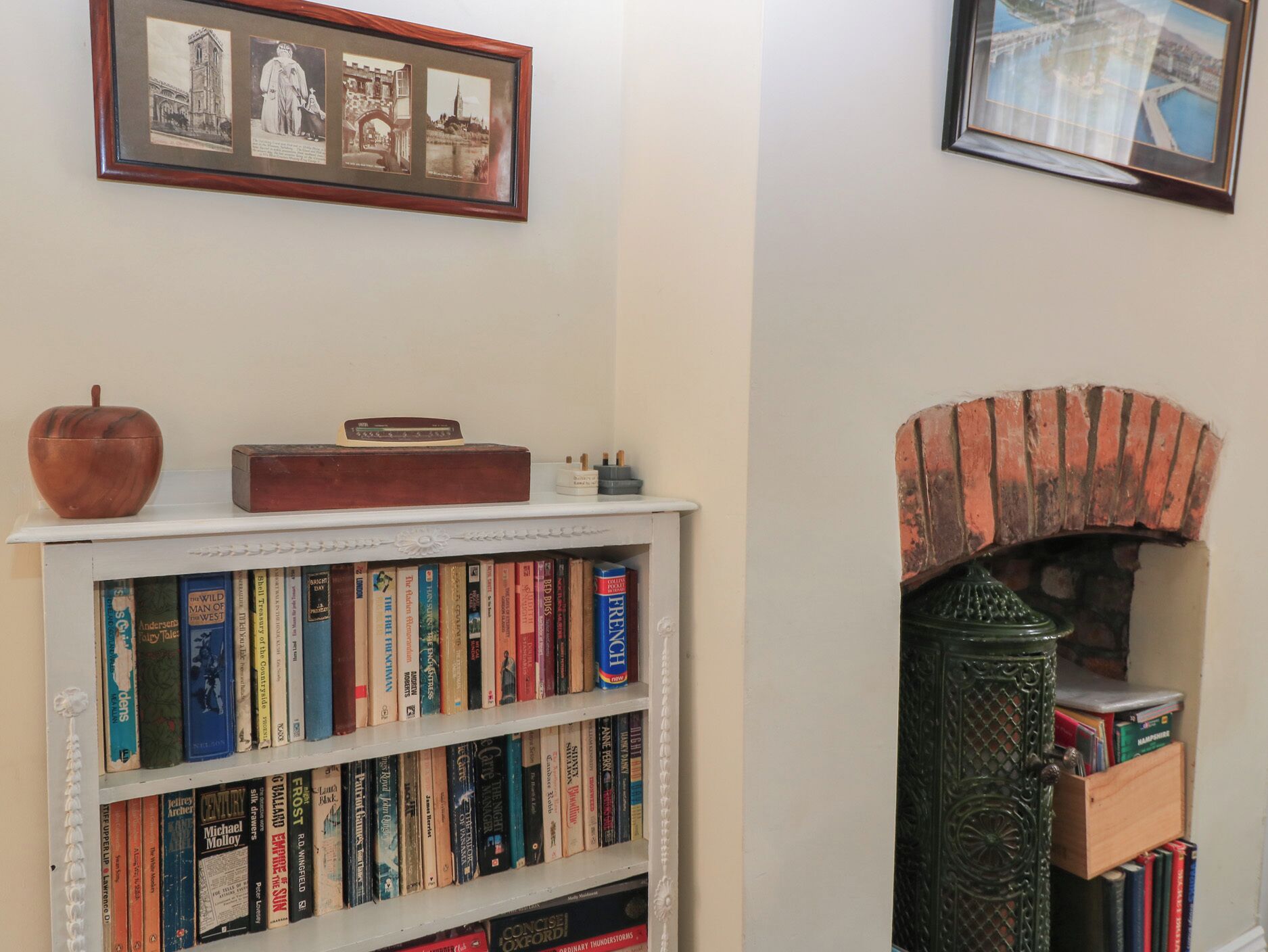 Uma estante com livros, um quadro emoldurado e uma lareira de tijolos.