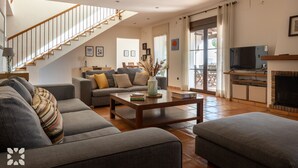 A modern living room with a staircase, grey sofas, a coffee table, and a fireplace. - Villa HARMONIA by Abahana Villas (Teulada)