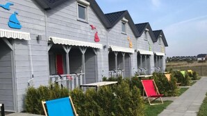 Een rij grijze gebouwen met een rij rode stoelen en een blauwe stoel ervoor.