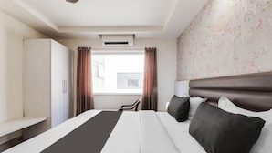 A hotel room with a bed, a wardrobe, a window with curtains, and a ceiling fan. - Collection O Civil Lines Near Old Bus Stand (Bareilly)