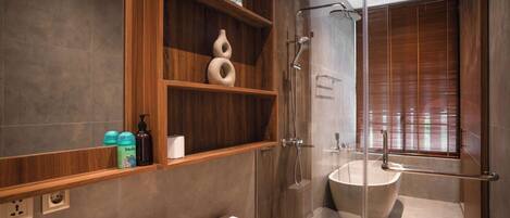 Une salle de bain moderne dotée d’une douche à parois de verre, d’une baignoire sur pieds et d’étagères en bois où sont rangés les articles de toilette.