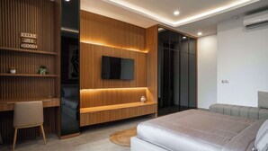 Un dormitorio moderno con una cama, un escritorio y un televisor fijado a una pared de madera.