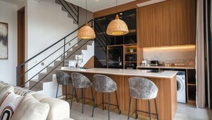 Una cocina moderna con una isla central, taburetes de bar y lavadora integrada.