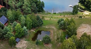 An aerial view of a lakeside property with a small pond, dense trees, and a dock. - Comfortable Holiday Homes Right on the Lake (Czaplinek)