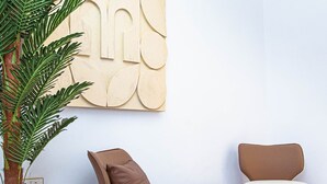A modern interior with a large potted plant, two cushioned chairs, and a marble floor. - TM Luxe Stays Apartment  (Ibadan)