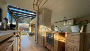 A modern kitchen with wooden cabinets, a built-in oven, and a large window. - Design villa with glass roof and parquet flooring, garden and fitness center near downtown (Montpellier)