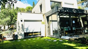 A modern two-story house with a garage, a covered patio area, and a well-maintained lawn. - Design villa with glass roof and parquet flooring, garden and fitness center near downtown (Montpellier)