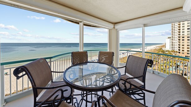 A balcony with a glass table and chairs, overlooking a beach and ocean. - Beach Colony W7C - Covered Parking Included (Perdido Key)