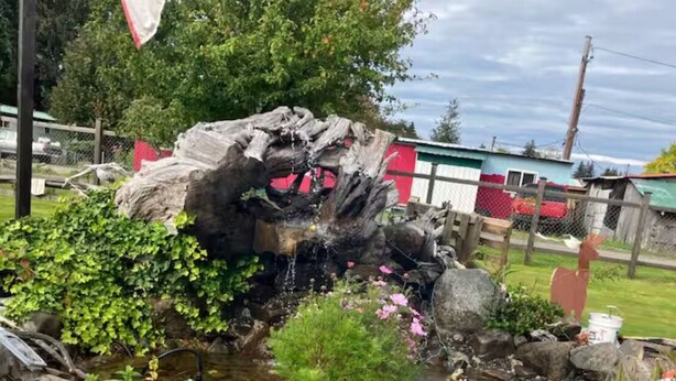 A rustic outdoor setting with a fire pit, a wooden stump, and a small stream. - RV in charming Forks with WiFi, AC. Happy travel and 1 block from Bella’s house! (Forks)