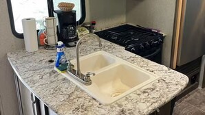 A compact kitchen with a sink, stove, and microwave. - RV in charming Forks with WiFi, AC. Happy travel and 1 block from Bella’s house! (Forks)