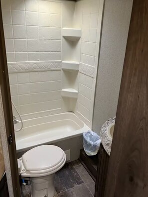 A small bathroom with a white toilet, a bathtub, and a shower.