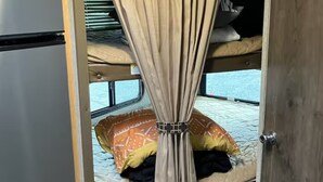 A compact room with a bunk bed, a small kitchenette, and a curtain. - RV in charming Forks with WiFi, AC. Happy travel and 1 block from Bella’s house! (Forks)
