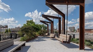 An outdoor seating area with benches and a metal structure, overlooking a cityscape. - Sosuite | 2BR Apt w W/D, Gym, On-Site Restaurant (Philadelphia)